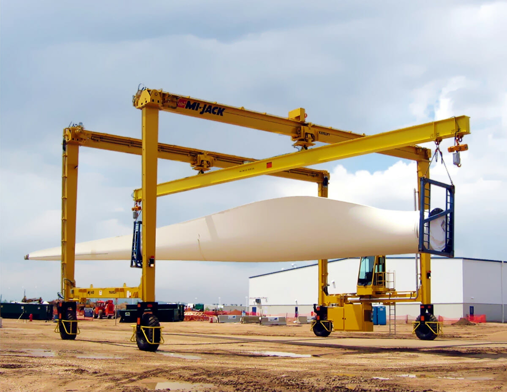 Wind Turbine Section Lifted By Two Travelifts With I Beams Featuring Center Swivels